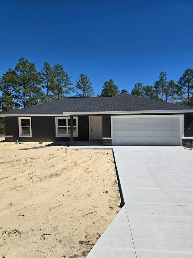 ranch-style home featuring a garage, concrete driveway, and roof with shingles