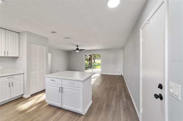 kitchen with light countertops, wood finished floors, white cabinetry, and a center island