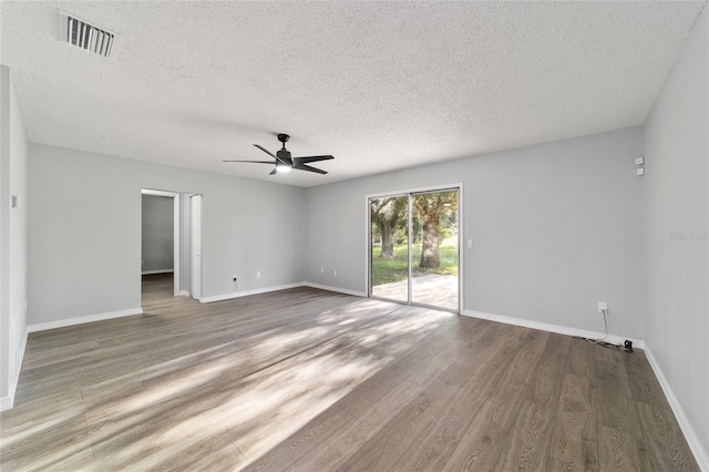 unfurnished room with baseboards, a textured ceiling, visible vents, and wood finished floors