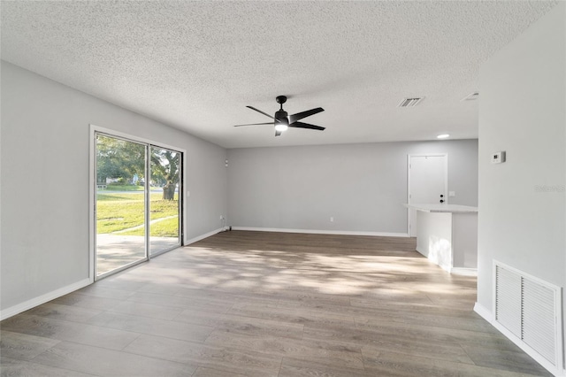 spare room with ceiling fan, wood finished floors, and visible vents