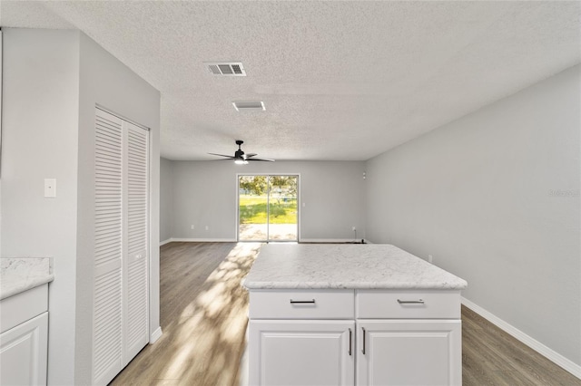 kitchen featuring visible vents, white cabinetry, open floor plan, light countertops, and light wood-type flooring