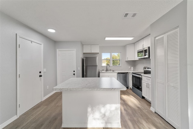 kitchen with stainless steel appliances, white cabinets, visible vents, and a sink