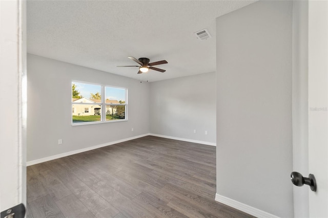 unfurnished room with visible vents, dark wood finished floors, a textured ceiling, and baseboards