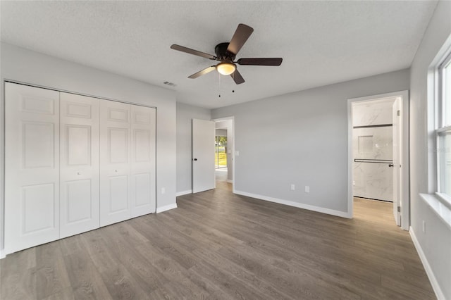 unfurnished bedroom featuring a closet, visible vents, baseboards, and wood finished floors