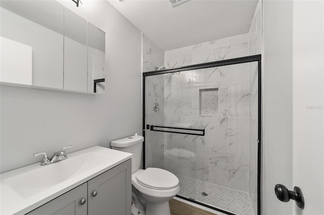 bathroom with toilet, vanity, and a marble finish shower