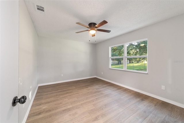 empty room featuring baseboards, a textured ceiling, visible vents, and wood finished floors