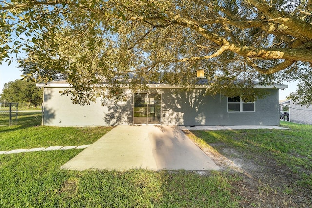 view of front facade featuring a patio, a front yard, fence, and stucco siding