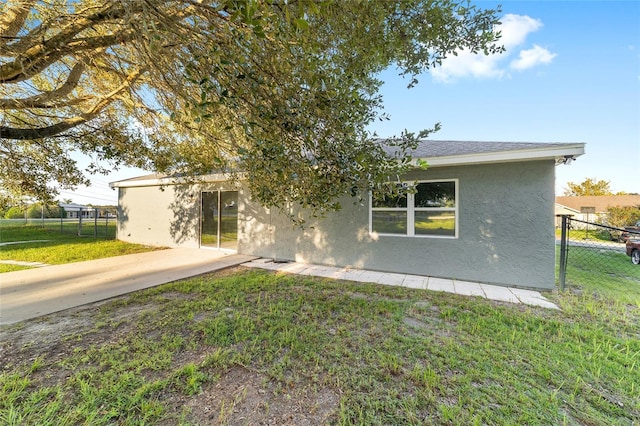 view of front of home with a shingled roof, a front yard, fence, and stucco siding