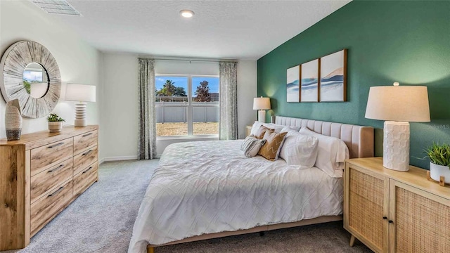 bedroom featuring baseboards, visible vents, a textured ceiling, and light colored carpet