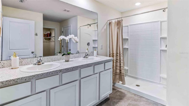 full bathroom with double vanity, a stall shower, visible vents, and a sink