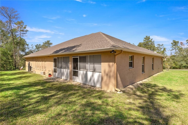 exterior space featuring a shingled roof, a yard, and stucco siding