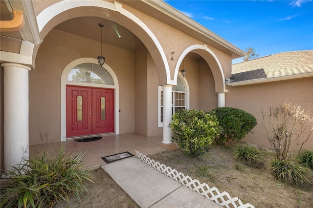 property entrance featuring roof with shingles and stucco siding