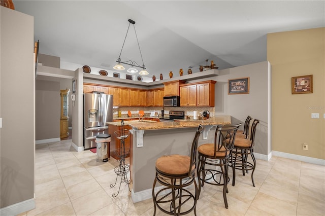 kitchen featuring light stone counters, a peninsula, vaulted ceiling, stainless steel appliances, and backsplash