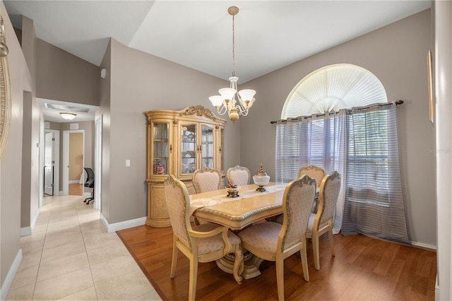 dining room with vaulted ceiling, light tile patterned flooring, a notable chandelier, and baseboards