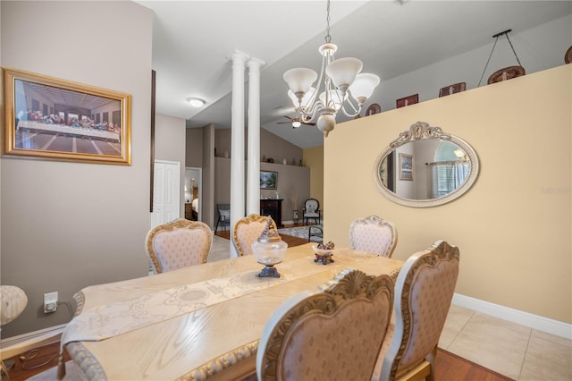 tiled dining space with lofted ceiling, decorative columns, baseboards, and a notable chandelier