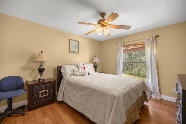 bedroom with ceiling fan, baseboards, and wood finished floors