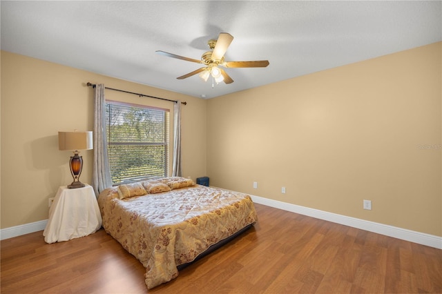 bedroom featuring ceiling fan, wood finished floors, and baseboards