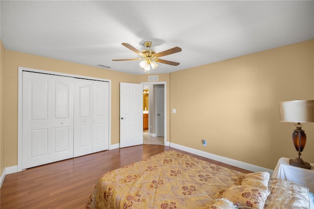 bedroom featuring a closet, visible vents, baseboards, and wood finished floors