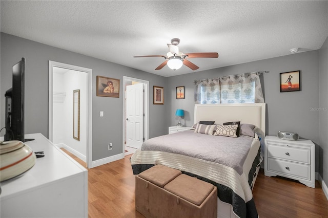 bedroom with light wood finished floors, ceiling fan, baseboards, and a textured ceiling