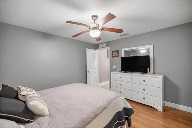 bedroom with a ceiling fan, light wood-type flooring, visible vents, and baseboards