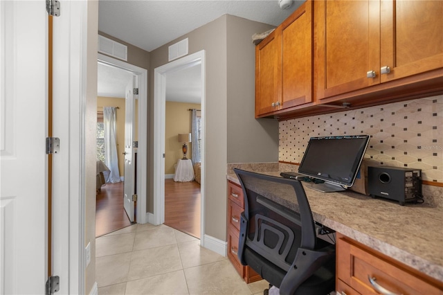 office area featuring built in desk, light tile patterned flooring, visible vents, and baseboards