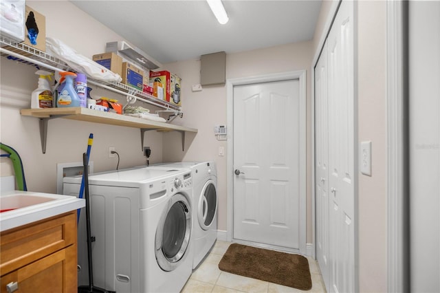 clothes washing area with light tile patterned floors, washing machine and dryer, and cabinet space