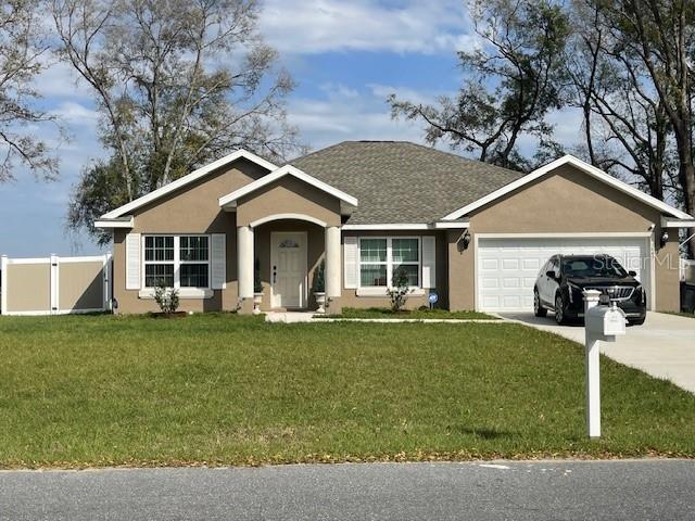 ranch-style home with a front yard, fence, and stucco siding