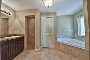 bathroom with a garden tub, vanity, and tile patterned floors