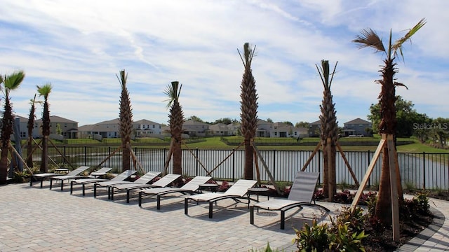 view of patio / terrace with a water view, fence, and a residential view