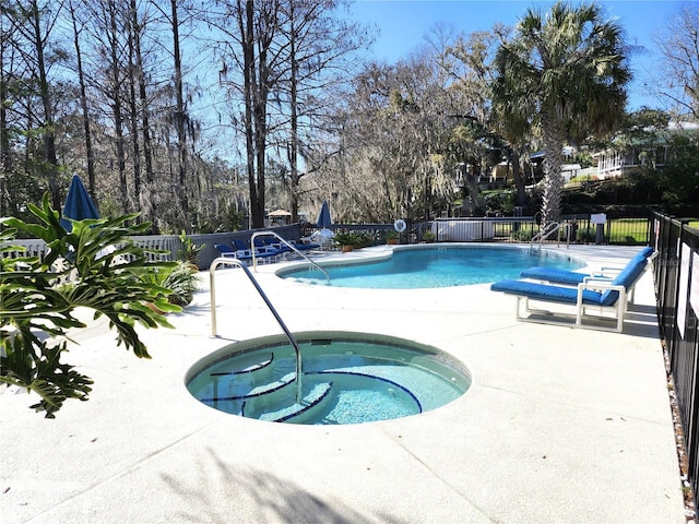 community pool with a patio, a hot tub, and fence