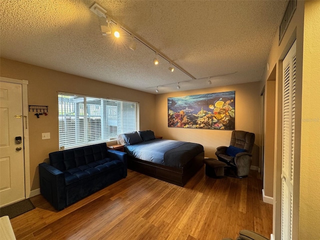 bedroom featuring a textured ceiling, baseboards, and wood finished floors