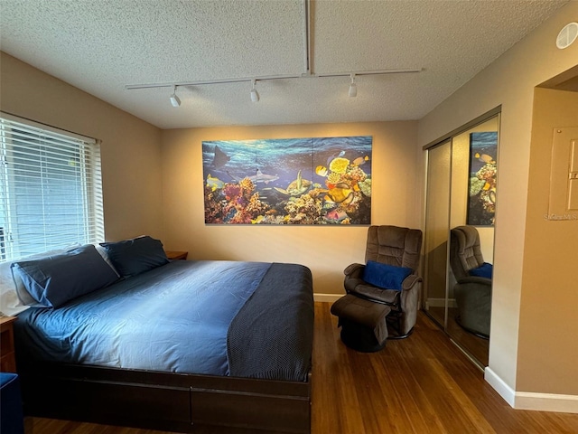 bedroom with a textured ceiling, a closet, wood finished floors, and baseboards