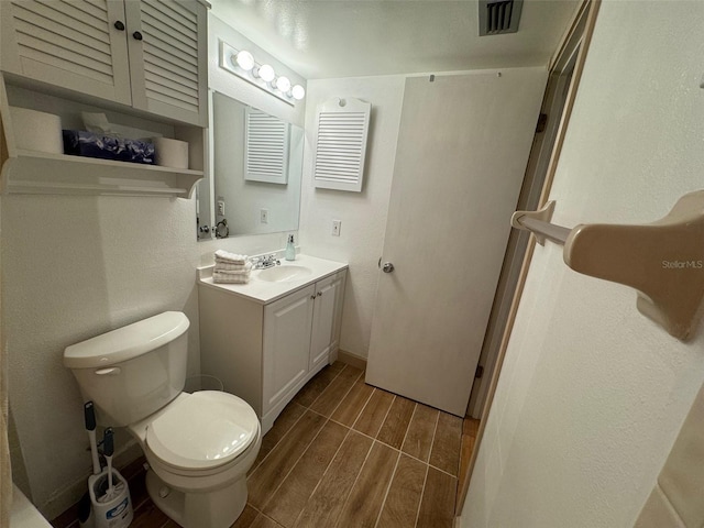 bathroom featuring toilet, wood finish floors, visible vents, vanity, and baseboards