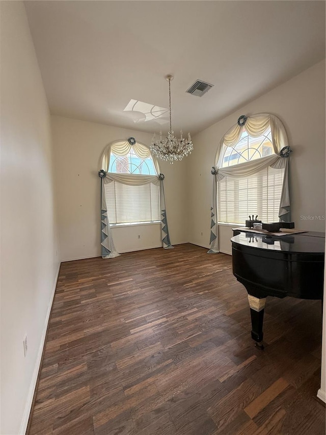 sitting room with visible vents, a notable chandelier, baseboards, and wood finished floors