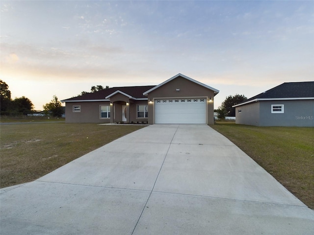 ranch-style home featuring stucco siding, driveway, an attached garage, and a yard