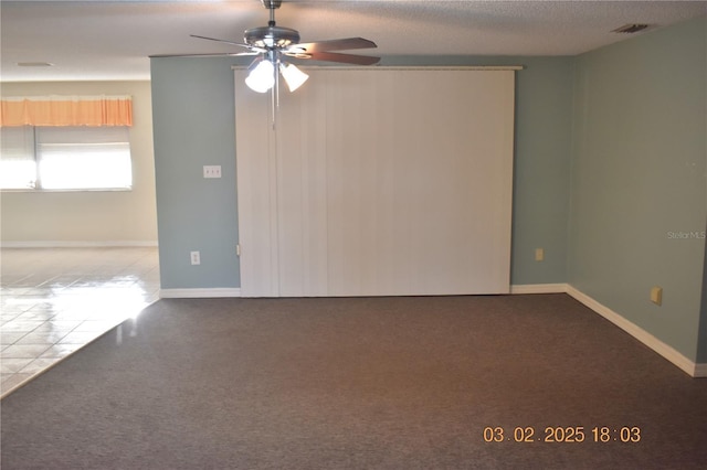 empty room featuring a ceiling fan, baseboards, visible vents, and a textured ceiling