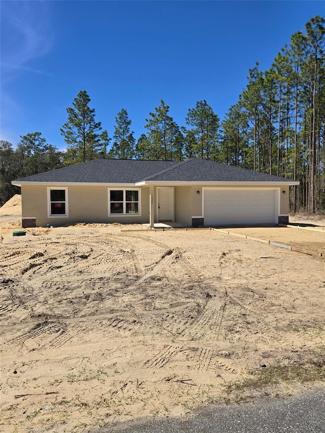 ranch-style home featuring an attached garage and stucco siding