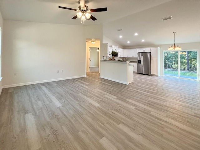 unfurnished living room featuring light wood-style flooring, ceiling fan with notable chandelier, visible vents, baseboards, and vaulted ceiling