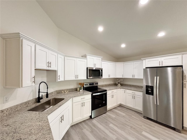 1370 SW Obee Ridge Rd, Dunnellon, FL 34432 - kitchen featuring stainless steel appliances, vaulted ceiling, white cabinetry, light stone counters, and light wood-type flooring