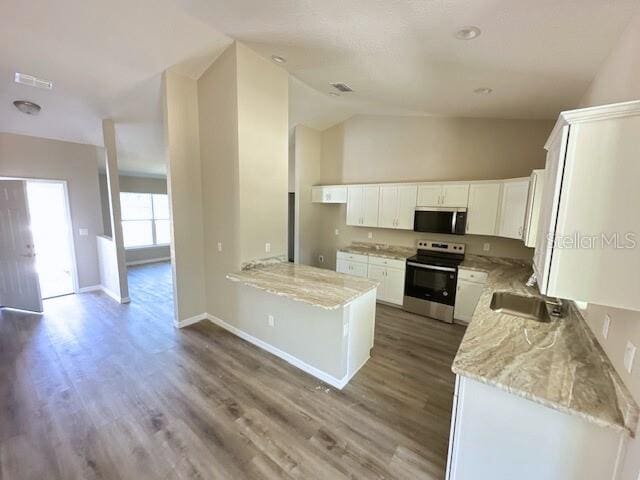 kitchen with a sink, light stone counters, wood finished floors, stainless steel appliances, and white cabinets