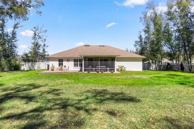 rear view of house with a yard, stucco siding, a fenced backyard, and a sunroom