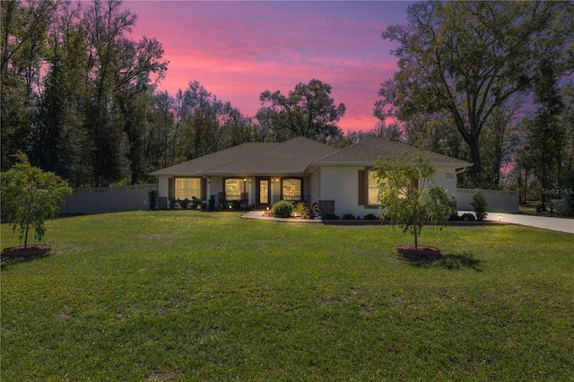 view of front of property featuring concrete driveway, fence, a front lawn, and stucco siding