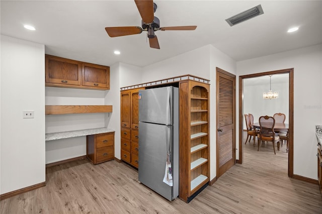 kitchen with open shelves, visible vents, light wood-style flooring, freestanding refrigerator, and built in study area