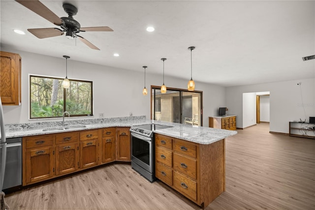 kitchen featuring light wood-style flooring, brown cabinets, a peninsula, stainless steel appliances, and a sink