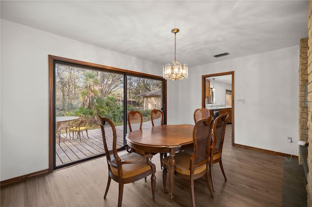 dining space with a chandelier, wood finished floors, visible vents, and baseboards