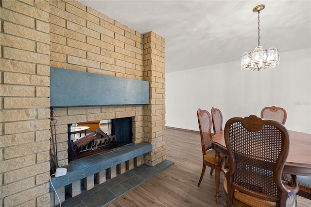 dining room with a brick fireplace and wood finished floors