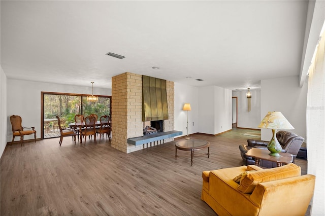 living room with a fireplace, wood finished floors, visible vents, and baseboards