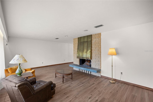 living room featuring visible vents, a fireplace, baseboards, and wood finished floors