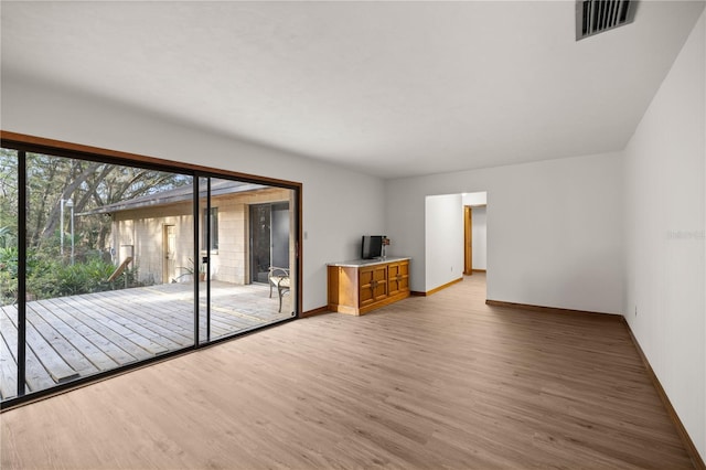 spare room featuring baseboards, visible vents, and light wood-style floors