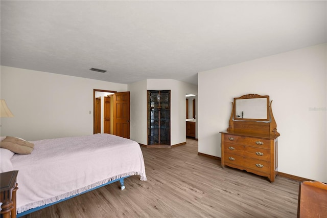 bedroom featuring light wood-style flooring, visible vents, and baseboards